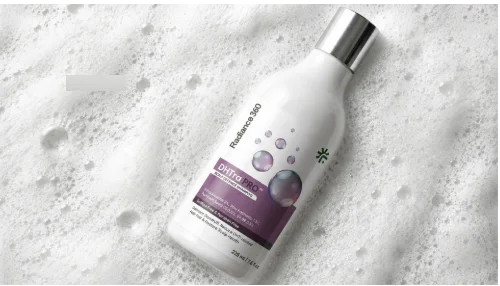 A white bottle of Radiance 360 DHTra PRO Anti-Dandruff Leave-On Serum resting on a surface covered in white foam bubbles.